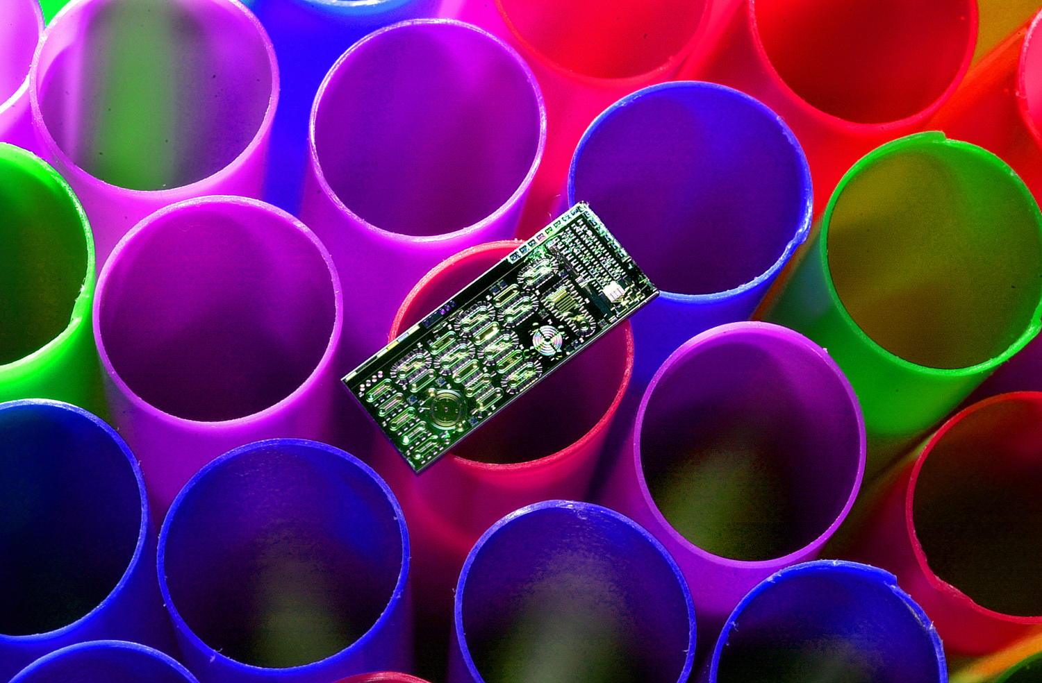 EIGHT MICRODEVICES, complete with microfluidic channels and drive motors, fit on a module resting on a soda straw end.