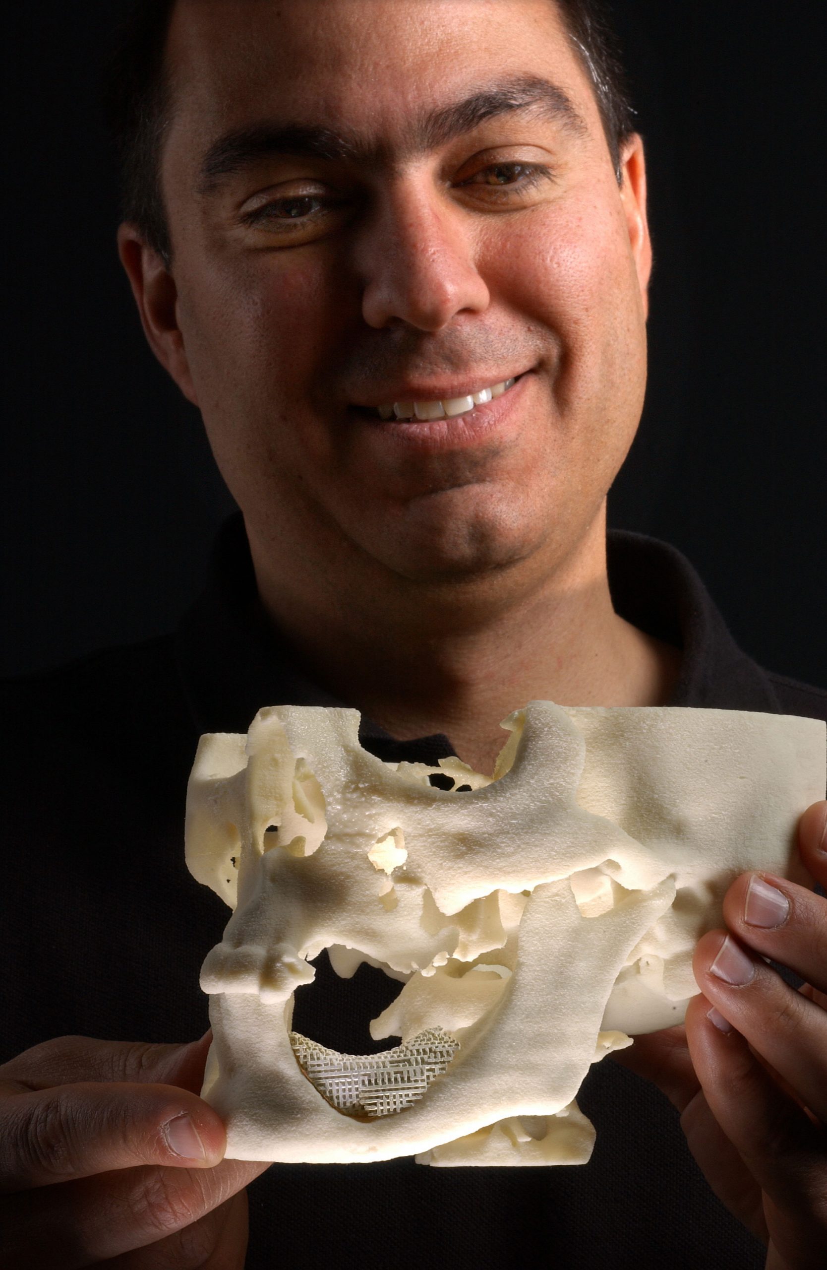 Pain-saving device brings pleasure to creator: Sandia researcher Joe Cesarano admires the perfect fit of his team’s Robocasted implant set in the jawbone of a manufactured skull. (Photo by Randy Montoya)
