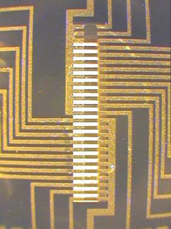Thin resistive gold heater elements suspended over a silicon nitride membrane. The elements, fed electrical current by the gold conductor lines, give researchers piano-key control in heating different portions of the device.