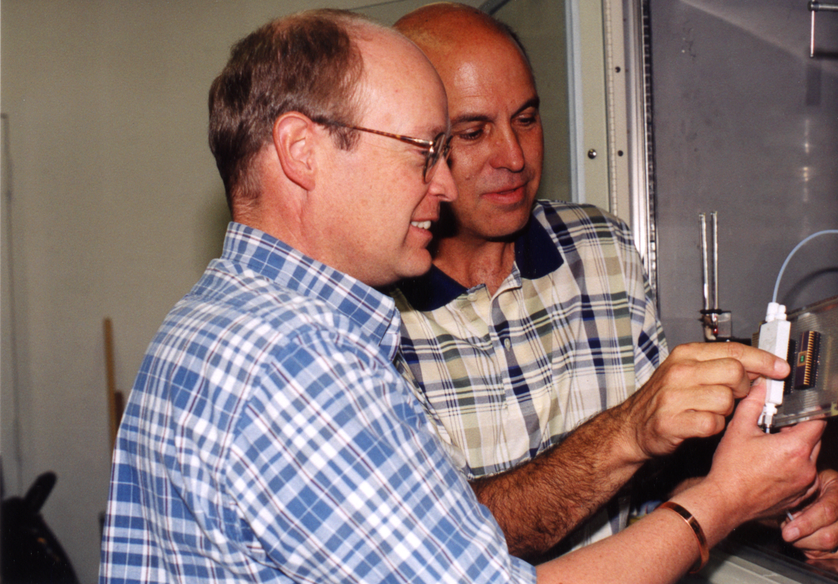 NEW APPROACH — Sandia researchers Charles Barbour, left, and Jeff Braithwaite prepare a combinatorial corrosion experiment on a single silicon wafer. The new experimental method promises to shed light on how and why copper corrodes in atmospheric environments.
