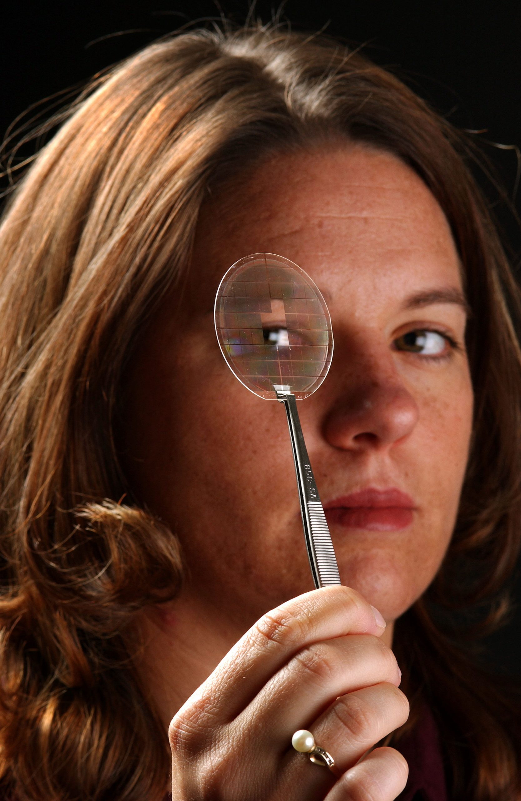CHRISTINE MITCHELL looks through a substrate that was made for the new cantilever epitaxy growth process. (Photo by Randy Montoya)