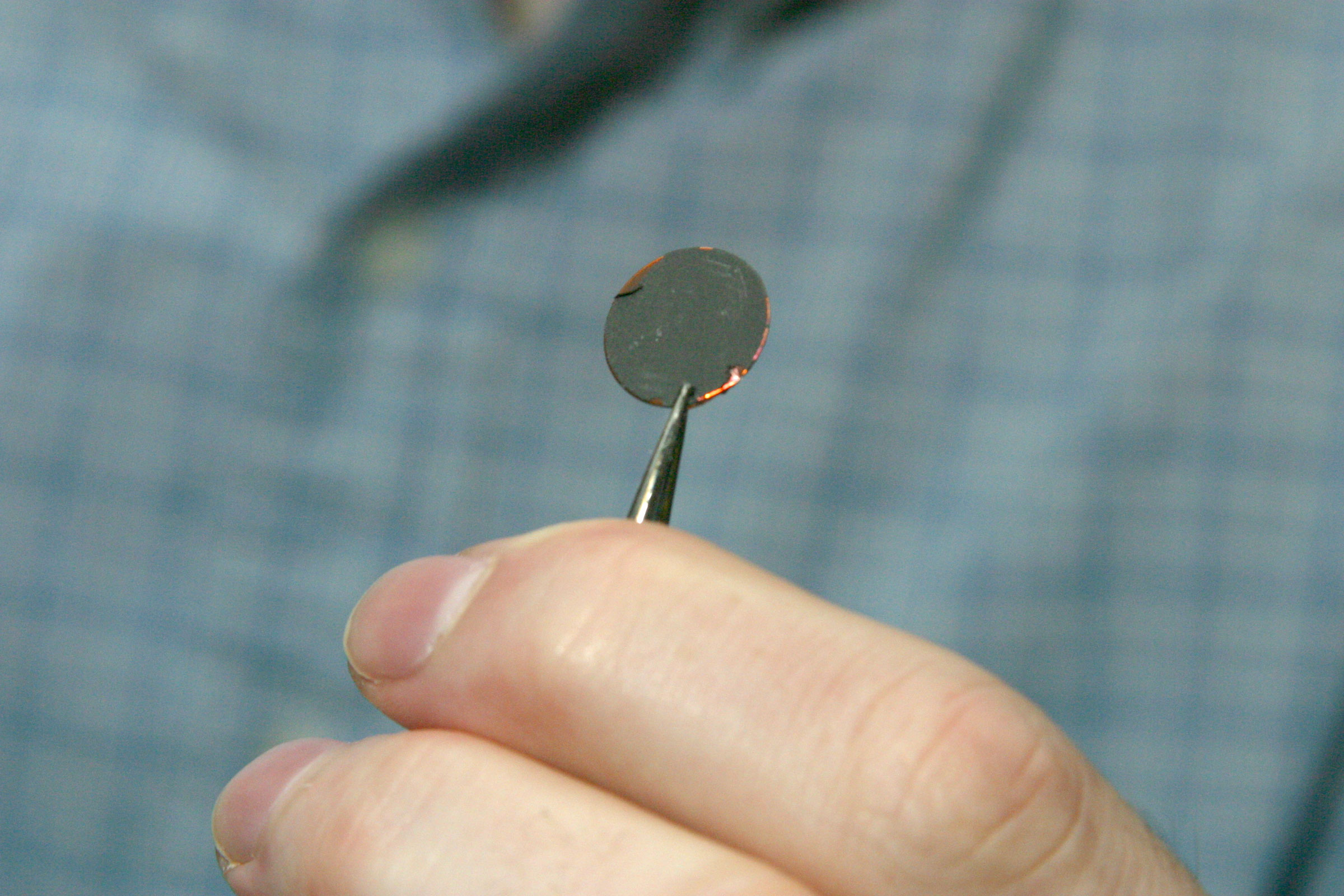 An electrode made by coating copper foil with the new silicon/graphite material, like the wafer-sized disc shown above, could serve as a more compact, longer lasting power source for rechargeable lithium-ion batteries.