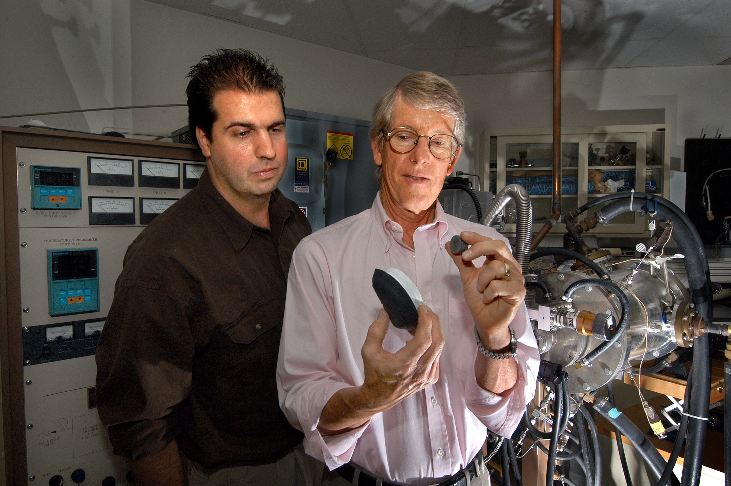 Sandia researchers Ron Loehman, right, and Dale Zschiesche check out material that can withstand twice the amount of heat compared to a conventional piece of a shuttle tile. (Photo by Randy Montoya)