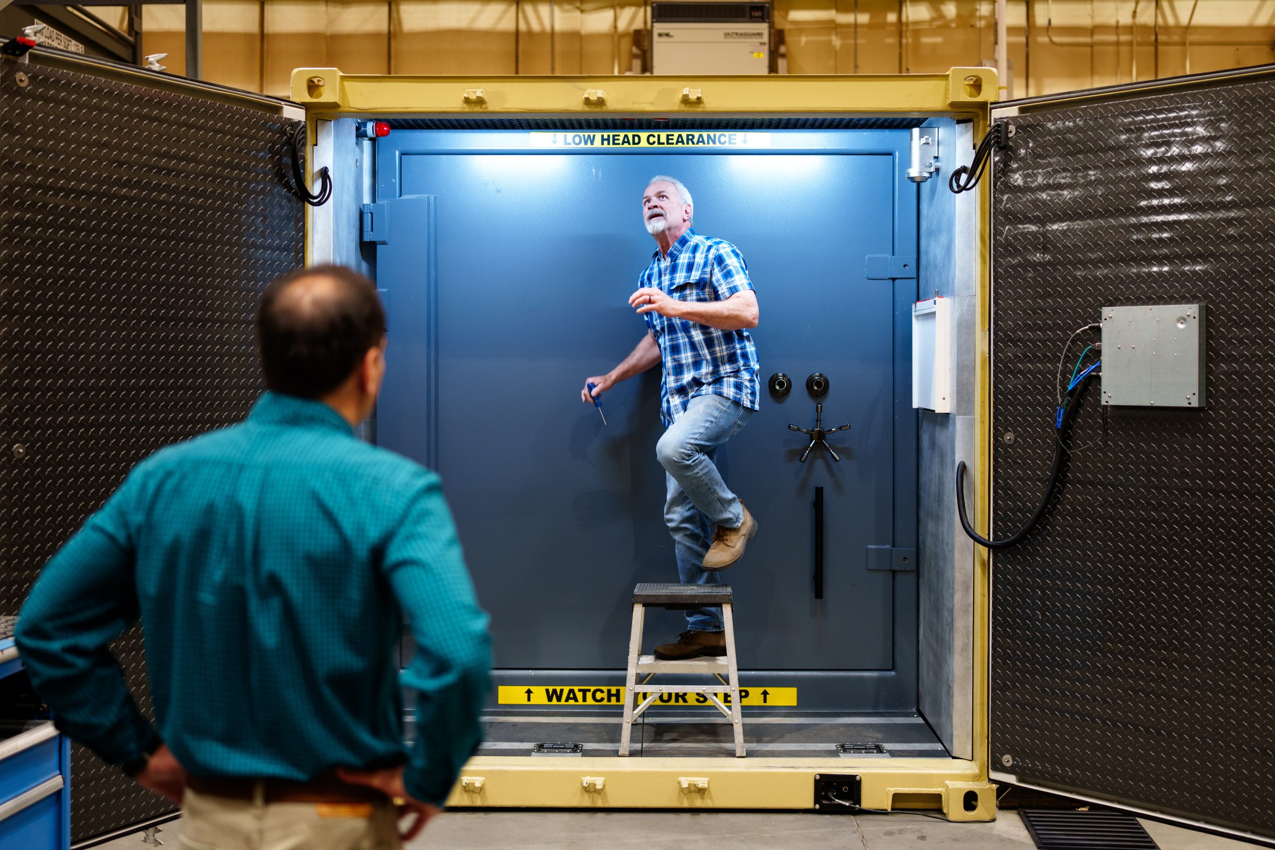 An engineer adjusts sensors inside of the Mobile Vault’s vestibule at Sandia National Laboratories while another watches. 