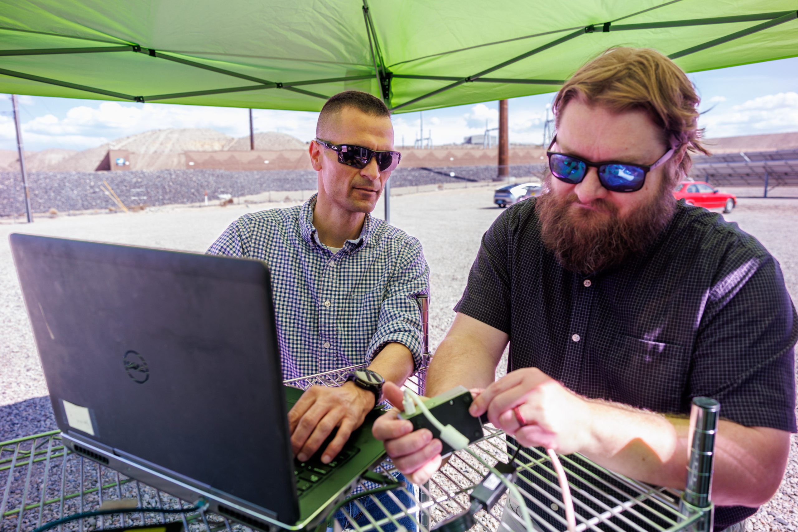 Sandia National Laboratories cybersecurity expert Adrian Chavez, left, and computer scientist Logan Blakely work to integrate a single-board computer with their neural-network AI into the Public Service Company of New Mexico’s test site. This code monitors the grid for cyberattacks and physical issues.