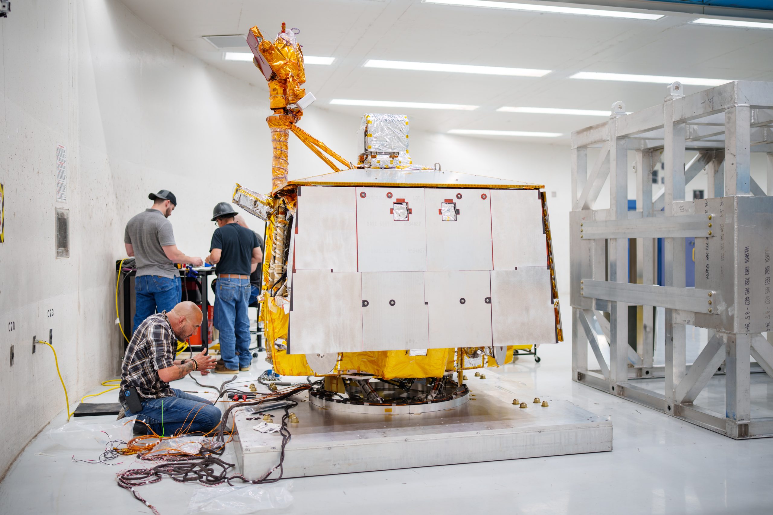 Orlando Abeyta works on wiring prior to placing a cage around and attaching the VIPER rover to the arm of the Superfuge at Sandia National Laboratories.