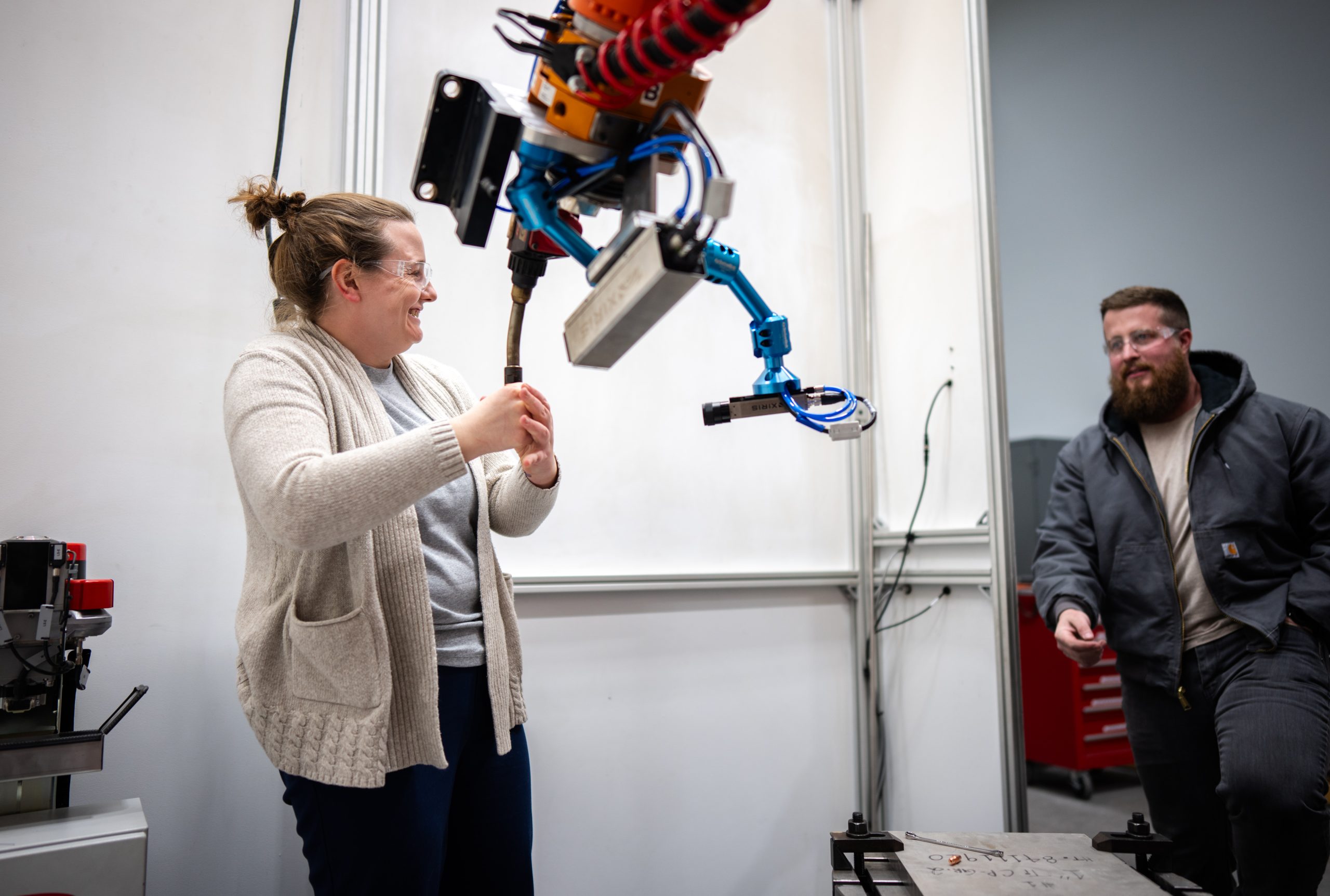Hannah Sims, left, and Levi Van Banstian, adjust a robotic arm on a Direct Energy Deposition system for additive manufacturing at Sandia National Laboratories' new CAMINO facility. 