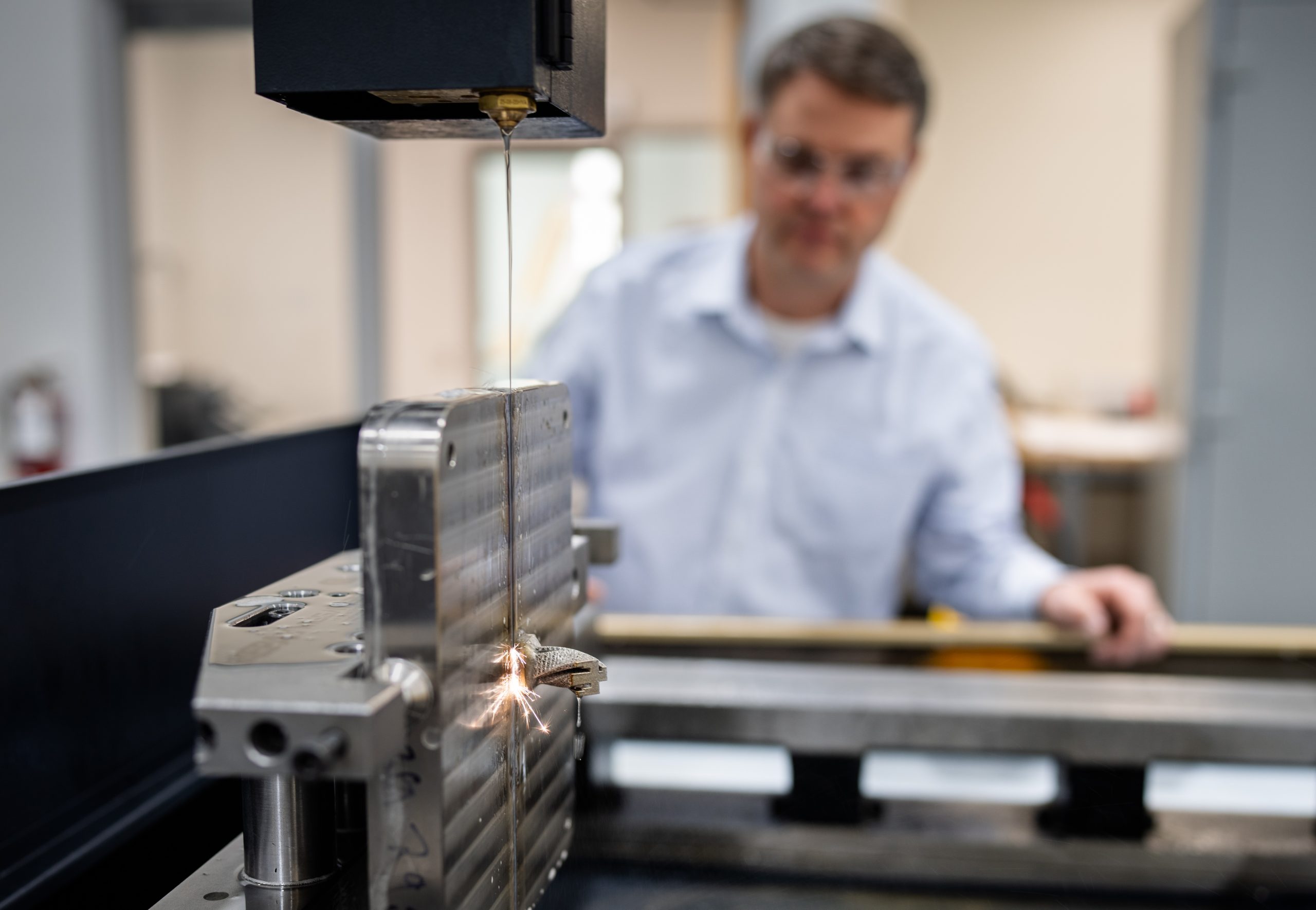 Dale Cillessen uses a wire electrical discharge machine to cut a metal sample piece at Sandia National Laboratories' CAMINO facility. 