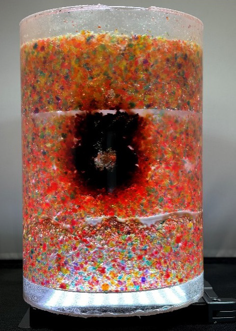 A container protected with Sandia National Laboratories' “Bleeding Materials and Enclosures” product indicates a tamper attempt. In this image, silicone is used to encapsulate the air-sensitive beads.