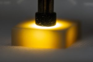 <strong>Technicians at Sandia National Laboratories use a small wand of light and a microscope to manually inspect ceramic components for tiny defects. The process is time-consuming, challenging on the eyes and requires extensive training. With the introduction of artificial intelligence and new equipment, inspections will take place earlier in the production process. </strong>(Photo by Craig Fritz) Click on the thumbnail for a high-resolution image.