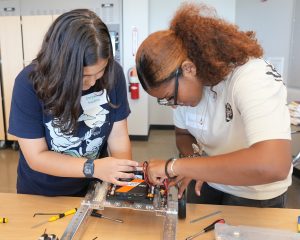 <strong>Two students apply the finishing touches to their built-from-scratch robot during the 2025 HMTech Program.</strong> (Photo courtesy of Sandia National Laboratories) Click on the thumbnail for a high-resolution image.