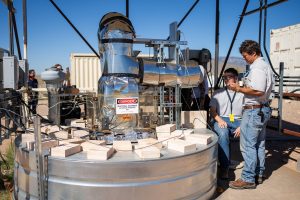 <strong>Sandia National Labs engineer Luke McLaughlin talks to colleague Henk Laubscher during a coffee roasting experiment at the National Solar Thermal Test Facility. The experiment used stored solar energy in a testbed to heat up the coffee roaster, as part of project with Michael Thomas Coffee.</strong>  (Photo by Craig Fritz) Click on the thumbnail for a high-resolution image.