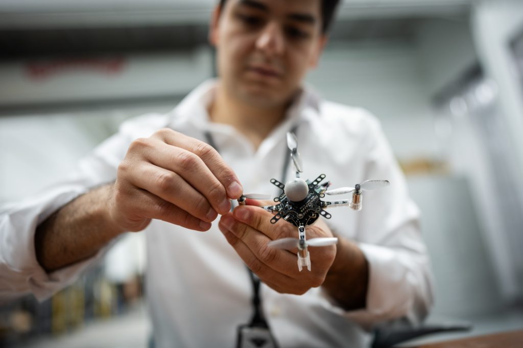 A man is snapping a new propeller onto a drone about the size of his hand.