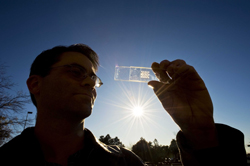 Sandia project lead Greg Nielson holds a solar cell test prototype with a microscale lens array fastened above it. Together, the cell and lens help creae ca concentrated photovoltaic unit. (Photo by Randy Montoya)