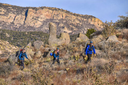 Three hikers with lovely rock formations and mountain crests in the background.