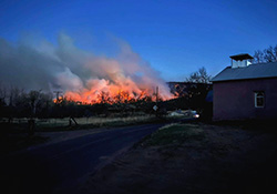 flames at dusk with house in the foreground 