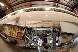 Sandian Kevin Howard inspects electrical wiring in the wheel well of a retired Boeing 727 at Sandia's FAA Airworthiness Assurance NDI Validation Center.  The wing on the 727 has been removed.