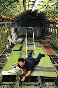 Adam Hoke, an aviation maintenance technician with the U.S. Coast Guard, inspects the belly of a Boeing 737 using an eddy current scanner. (Photo by Randy Montoya)