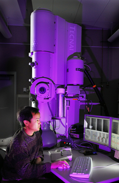 Sandia researcher Jianyu Huang sits in front of a combination TEM-STM microscope similiar to the one he used to image buckyball births. On the computer screen are images of flaws occurring in nanocylinders, a continuing area of research for Jianyu at the joint Sandia/Los Alamos CINT center.