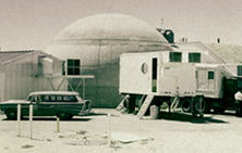 This photo, taken in the early 1960s, shows the reactor building and the original instrumentation building. The domed structure is the Reactor building, called the Kiva, and the metal building next to the Chevy Nomad is the Instrumentation Building. 
