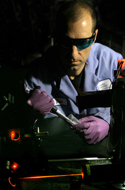 Sandia biochemist Dan Throckmorton prepares to add a sample to the prototype diagnostic device.  After Dan adds the sample, computer-controlled electronics direct a series of sample analysis steps.  Laser-induced fluorescence is used for highly sensitive detection of assay products. The final diagnostic device will feature a miniaturized, portable fluorescence detector.