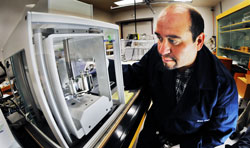 Ben Casados, Sandia technologist, looks at kilogram samples in a mass comparator.  