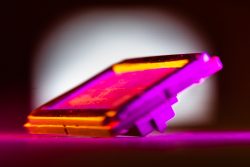A close-up of a rectangular device under a purple light.