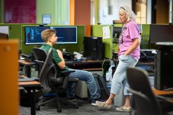 A woman and a young man talk in a colorful office space.