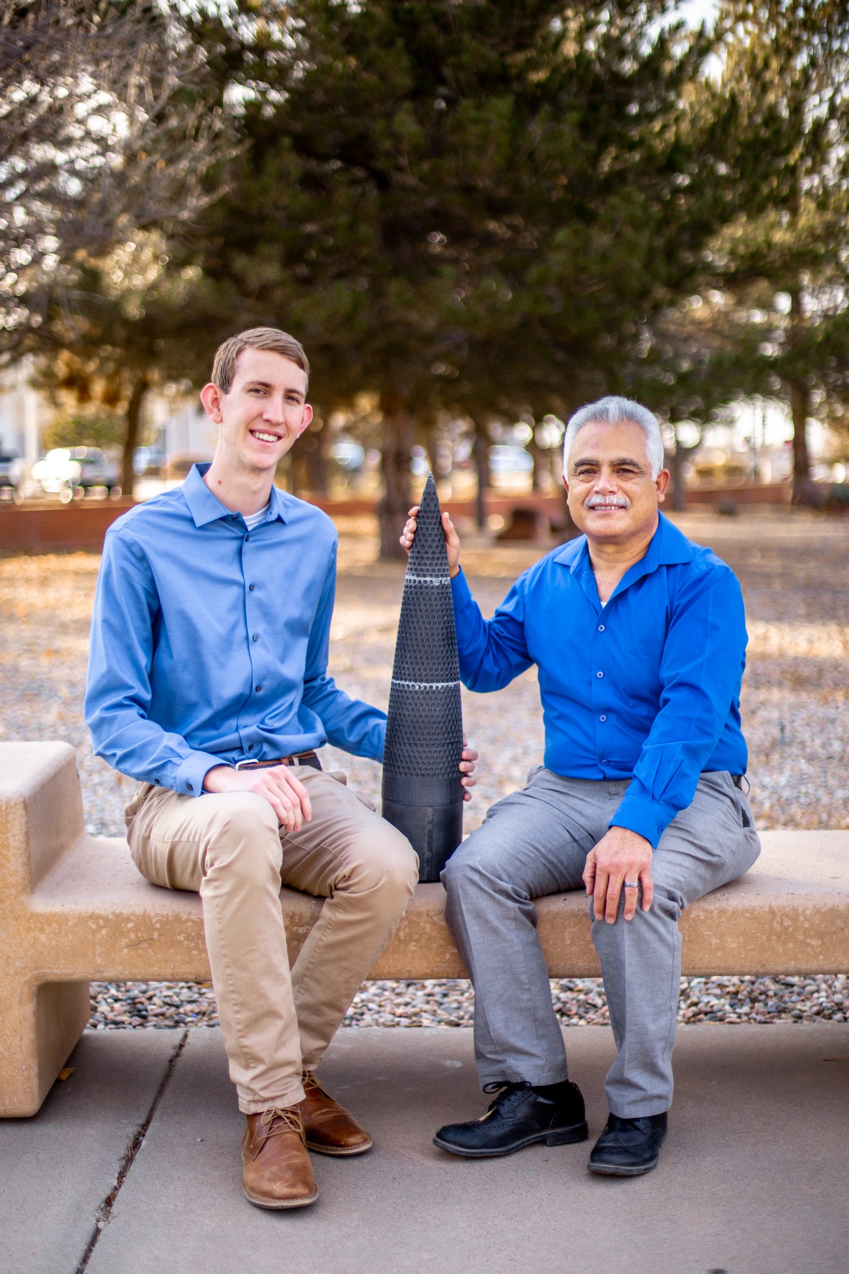 Graham Monroe, left, and Sal Rodriguez display the dimpled rocket nose they built as part of a collaboration between Sandia and the University of New Mexico.