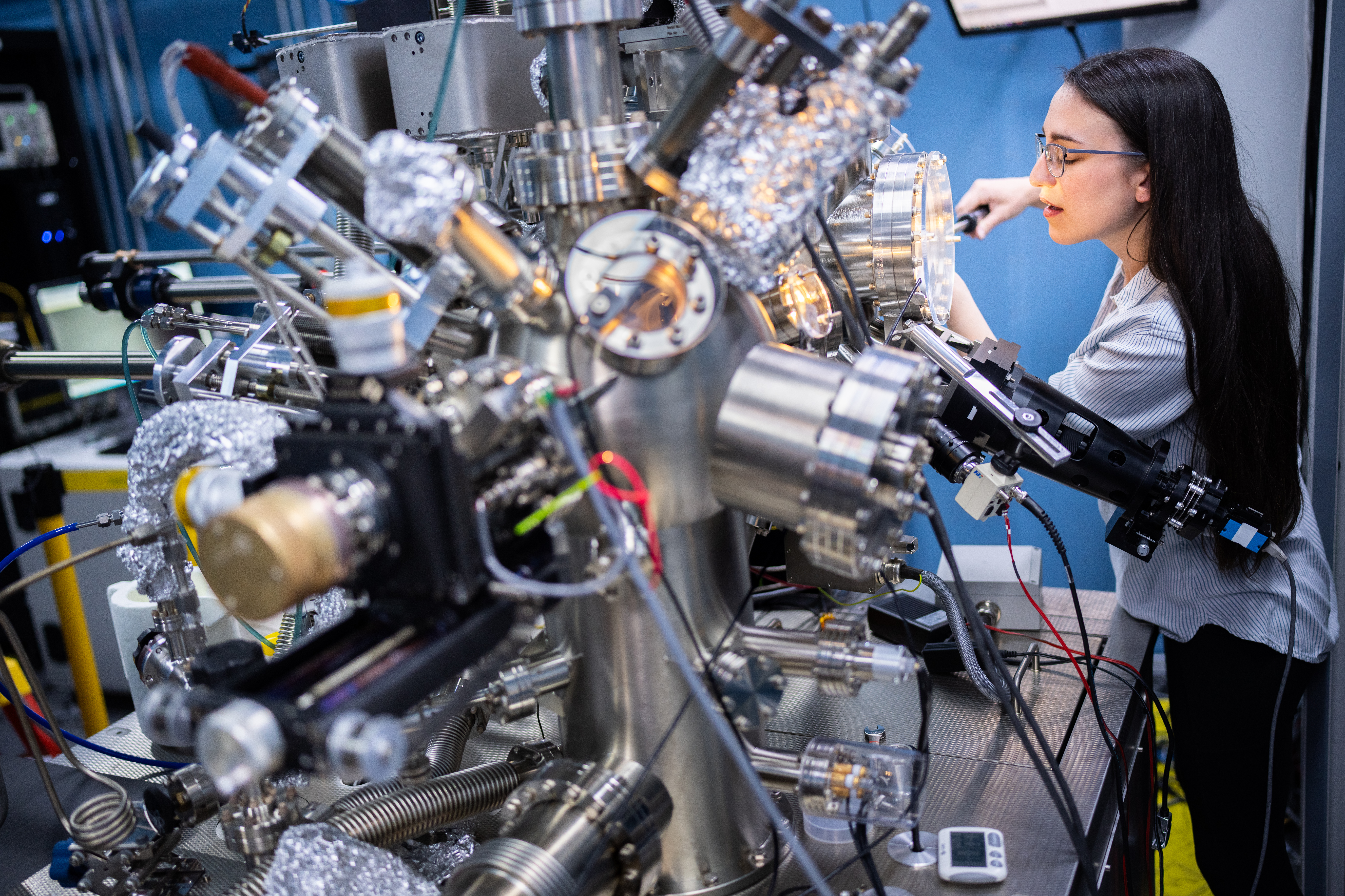 Caitlin McCowan adjusts a customized scanning tunneling microscope at Sandia National Laboratories. Not only can this machine capture images of atoms, but it can also manipulate them. 